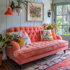 a living room with an orange couch and potted plants on the wall next to it