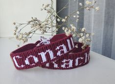 two knitted headbands sitting on top of a table next to a vase with flowers