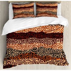 an orange and black bed with two pillows on top of it, in front of a white wall