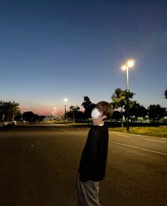 a person wearing a face mask standing in the middle of an empty street at night