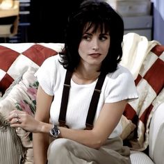 a woman sitting on top of a couch wearing suspenders