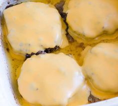 four hamburger patties covered in gravy in a white casserole dish