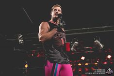 a man holding a microphone while standing on top of a wrestling ring