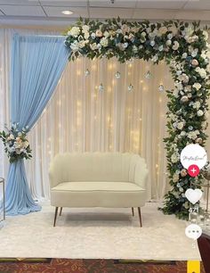 a white couch sitting in front of a blue drape covered wall with flowers on it