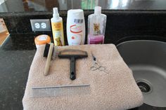 a hairbrush, comb, and other items are sitting on a towel in front of a sink