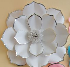 paper flowers are arranged on the wall next to scissors and other crafting supplies,