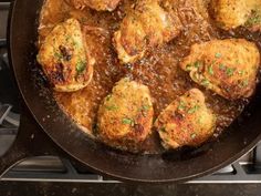 some meat patties are cooking in a skillet on the stove top with gravy