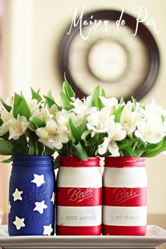 three red, white and blue mason jars with flowers in them sitting on a tray