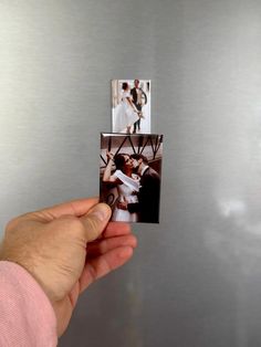 a person holding up three photos in front of a metallic refrigerator with the door open