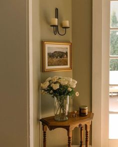 a vase with white flowers sitting on a table in front of a door and window