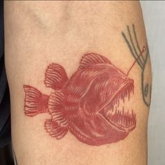 a red fish tattoo on the left thigh