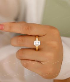 a woman's hand with a diamond ring on top of her finger, showing the center stone