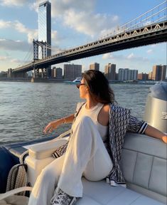 a woman sitting on the back of a boat in front of a bridge