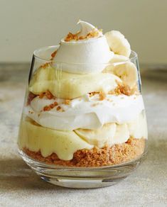 a dessert with bananas and whipped cream in a small glass bowl on a countertop