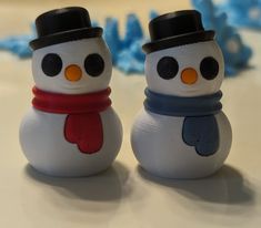 two plastic snowmen wearing hats and scarves