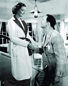 an old black and white photo of a woman shaking hands with a man in a suit