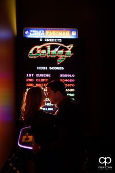 a man and woman standing in front of a neon sign