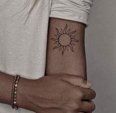 a woman's arm with a small sun tattoo on the left side of her arm