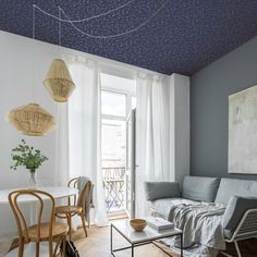 a living room filled with furniture and a painting hanging on the wall above it's windows