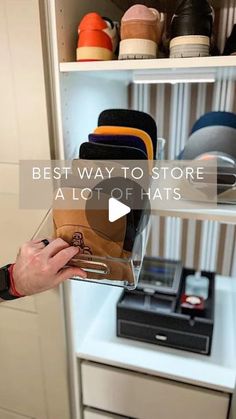 the man is holding his hat in front of some shelves with hats on it and other items