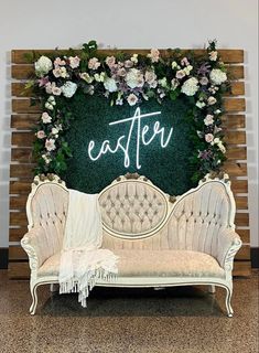 a white couch sitting in front of a green wall with flowers on it and the word easter