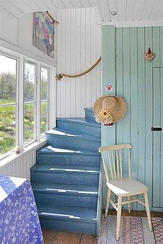 a chair sitting on top of a wooden floor next to a blue door and window