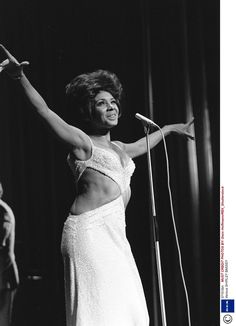 a black and white photo of a woman on stage with her arms in the air