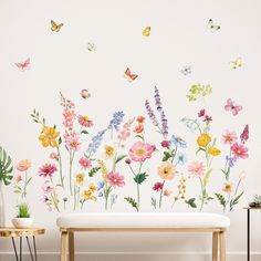 a bench sitting in front of a wall with flowers and butterflies on it