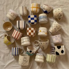 there are many coffee cups on the bed together, all different colors and designs in each cup