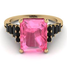 a pink tourmaline ring with black stones on the sides and gold band around it