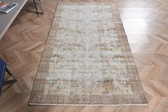 a rug on the floor in a room with wooden floors and a blue chair next to it