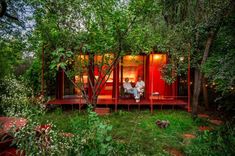 two people sitting on the porch of a red cabin