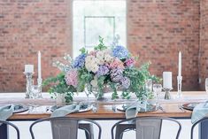 the table is set with silver chairs and flowers in vases on top of it