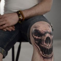 a man with a skull tattoo on his leg is sitting in front of the camera