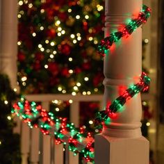 a christmas tree is in the background behind a white fence with green and red lights