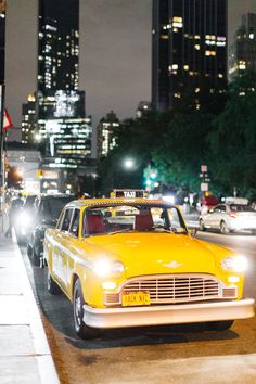 a taxi cab driving down a street next to tall buildings