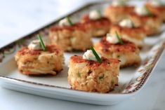 small appetizers are arranged on a white plate with green garnishes