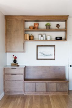 a wooden bench sitting in the middle of a living room next to a wall mounted shelf