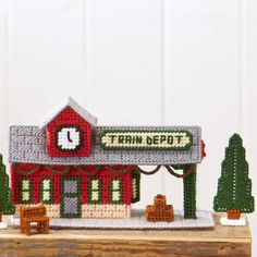 a small red building with a clock on the front and side of it that says train depot