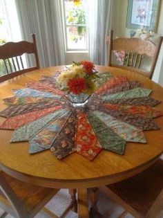 a wooden table topped with lots of different types of quilts on top of it