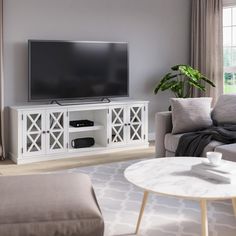 a living room with a large flat screen tv on top of a white entertainment center