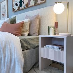 a bedroom with a bed, nightstand and pictures on the wall above it's headboard