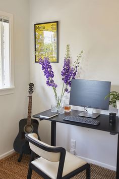 a desk with a guitar, vases and flowers on it in front of a window