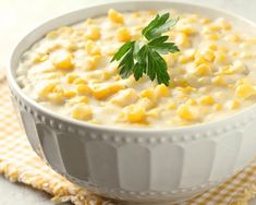 a white bowl filled with corn and garnished with parsley on the side