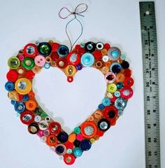 a heart shaped ornament made out of buttons is shown next to a ruler