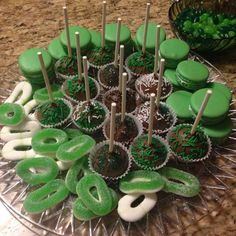 there are many green and white desserts on the plate with sticks in each one