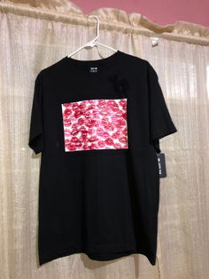 a black t - shirt with red and white print on the chest, hanging from a hanger