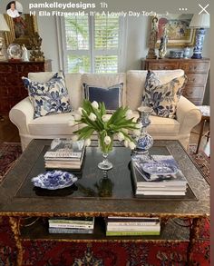 a living room filled with furniture and a coffee table covered in blue and white pillows