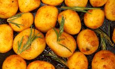 many potatoes with rosemary sprigs on them in a frying pan ready to be cooked