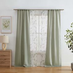 a living room with a window covered in green curtains and a potted plant next to it